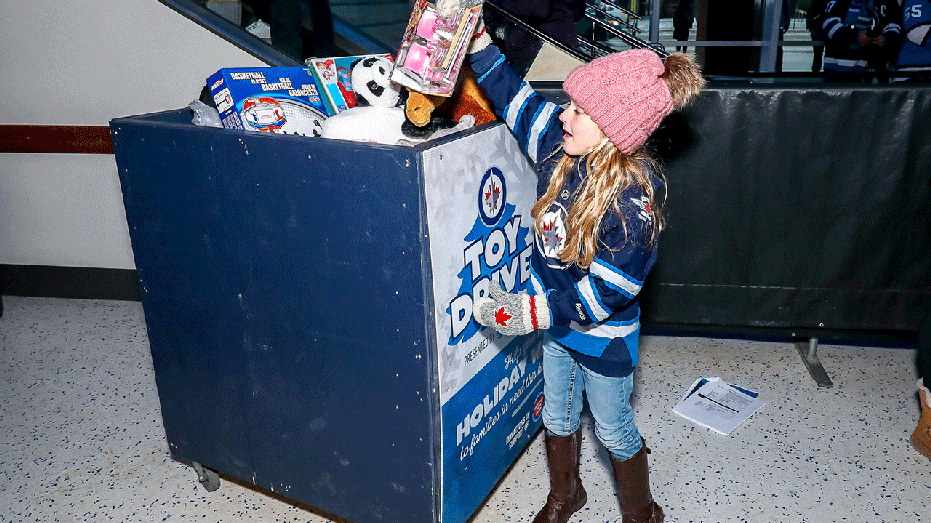 Girl putting toy into toy drive bin