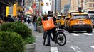 NEW YORK, NEW YORK - JULY 07: A delivery worker rides his bike on July 07, 2023 in New York City. Grubhub, DoorDash and Uber Eats sued the City of New York on July 6th in order to block its new minimum pay rules for food delivery workers. 