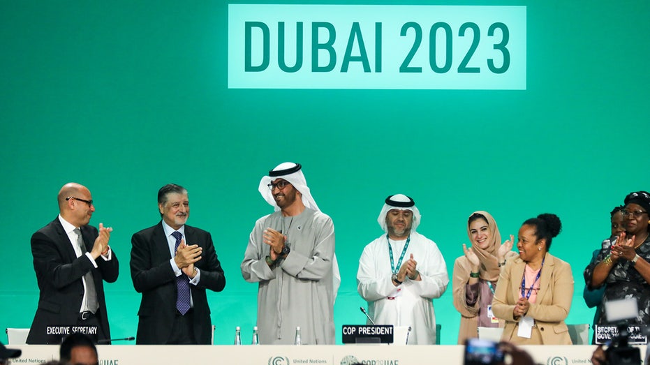 COP28 President Sultan Ahmed Al Jaber claps on stage with other climate delegates