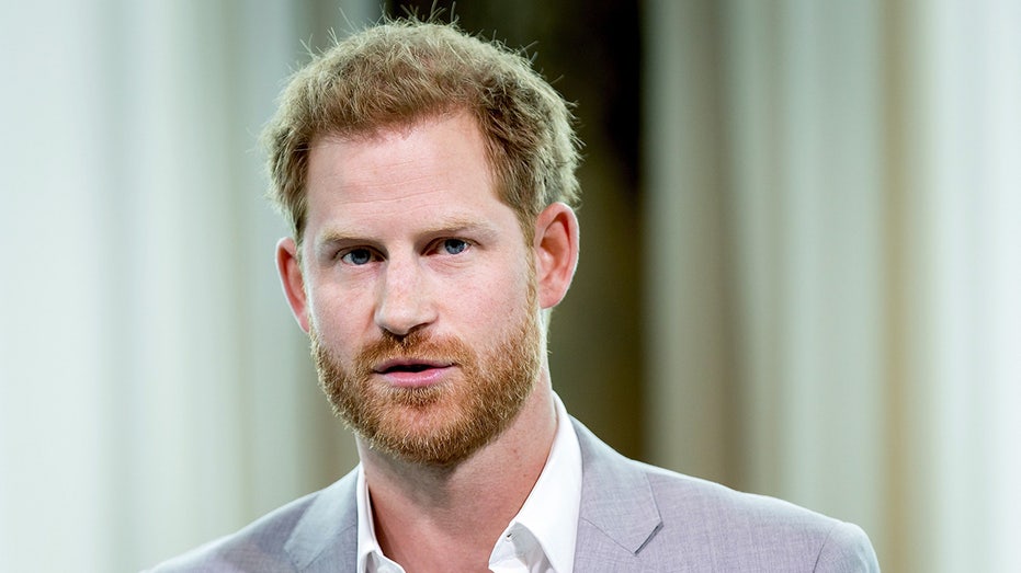 A close-up of Prince Harry wearing a light grey blazer and a white shirt