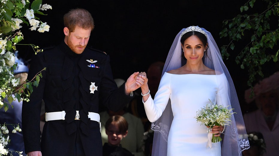 Meghan Markle in a wedding gown as her hand is held by Prince Harry in a suit