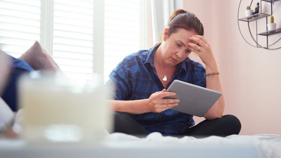 woman sits on bed looking stressed out