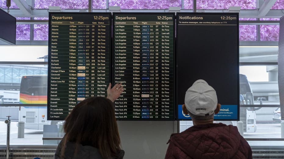 Travelers look at a departures information board at San Francisco International Airport (SFO) in San Francisco, California