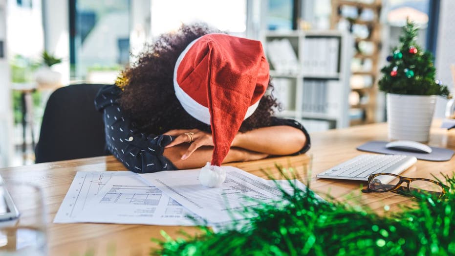 businesswoman wearing Santa hat, sleeping at her desk