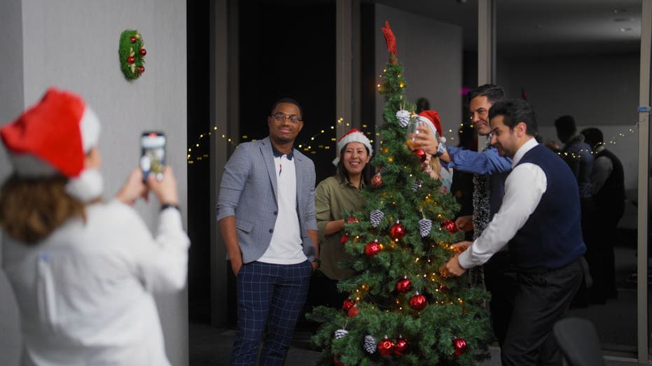 office workers posing for photo by Christmas tree