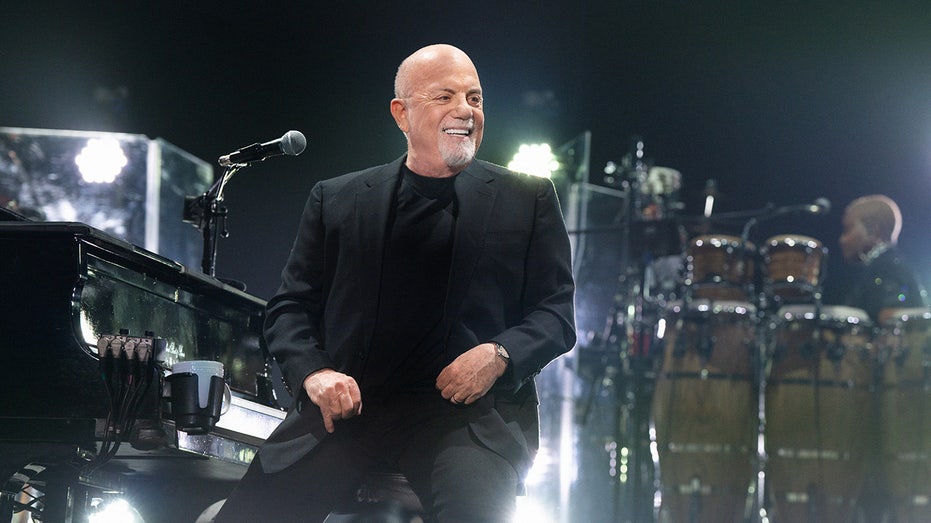 Billy Joel smiling during a concert in Elmont