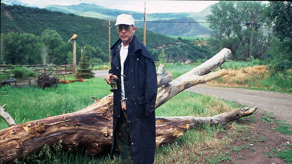 Hunter S. Thompson standing next to a fallen tree
