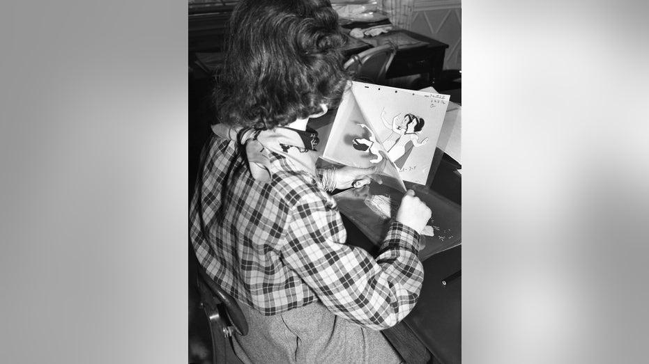 An animator working on sheets from the Snow White film