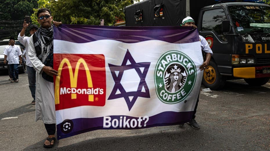 Protestors carry a flag with boycott McDonalds and Starbucks signs on a flag of Israel