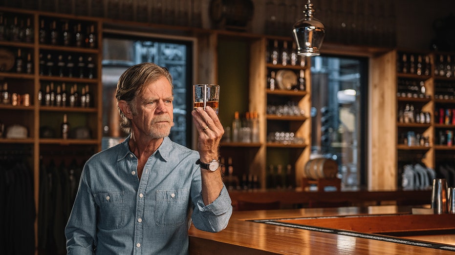 William H. Macy holding a glass of whiskey