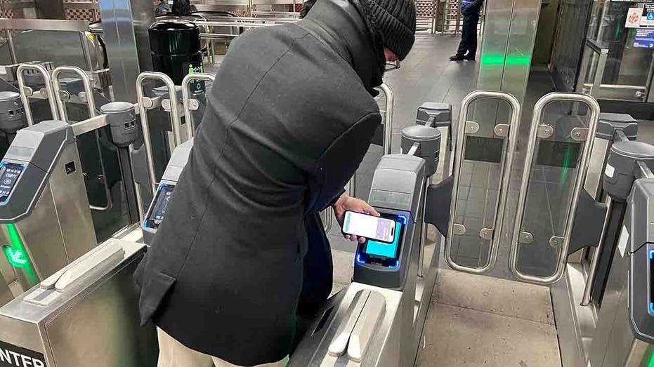 customer paying fare at subway gate