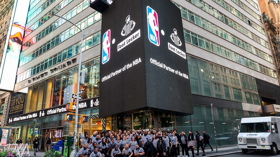 Foot Locker employees kneel in front of Foot Locker/NBA sign in Times Square