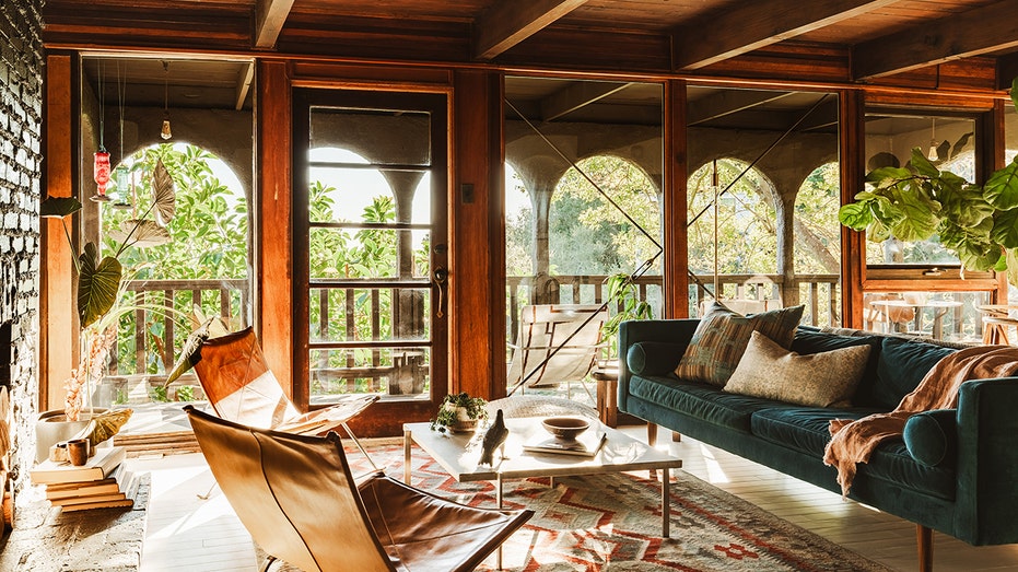 A living room with a green couch and many windows.