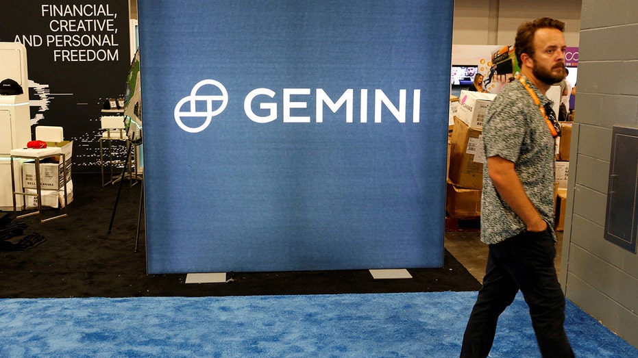 Photo of a man walking past the logo of Gemini Trust at a Bitcoin conference