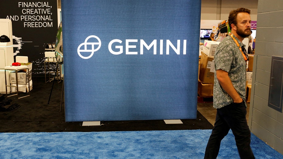 Photo of a man walking past the logo of Gemini Trust at a Bitcoin conference