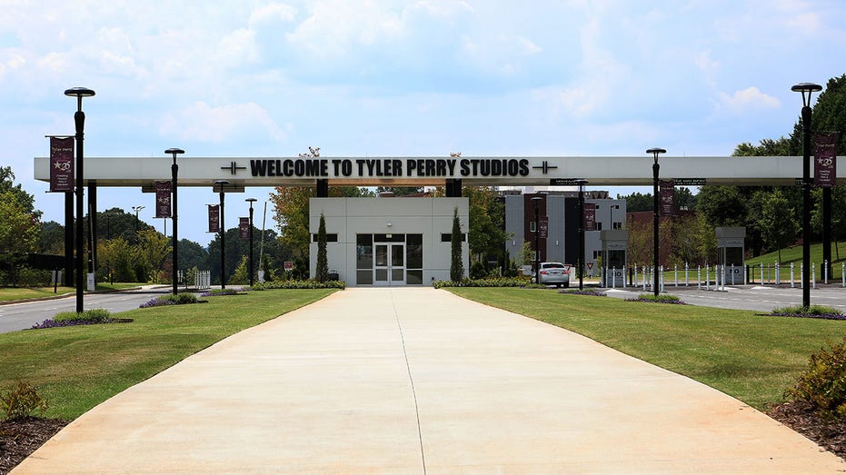 A picture of the exterior of Tyler Perry Studios in Atlanta with a hoirzontal sign overhanging a white building and tan walkway