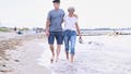 A retired couple walks arm in arm on the beach. - Fox News