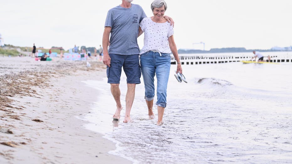 An older couple walking on beach