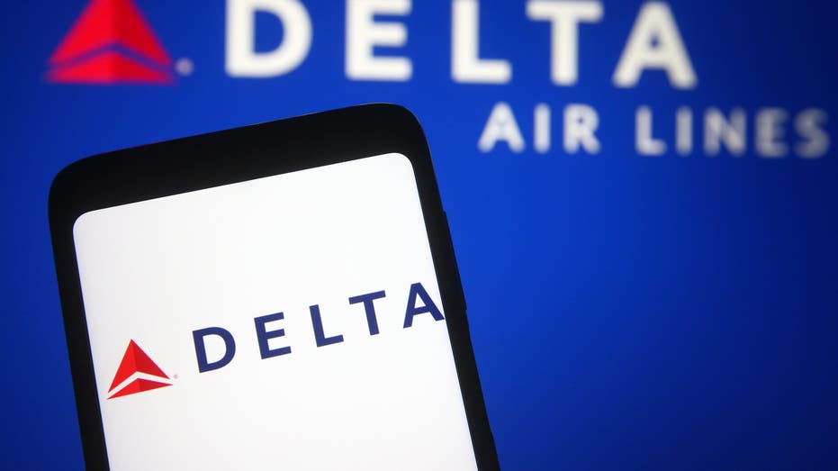 Delta app on cell phone with "Delta Air Lines" in background