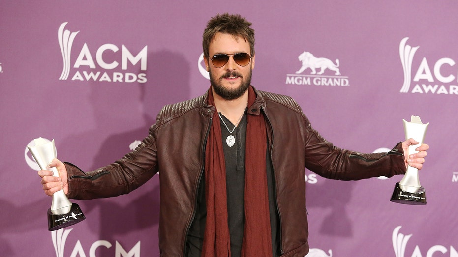 Eric Church holds out his arms after winning awards