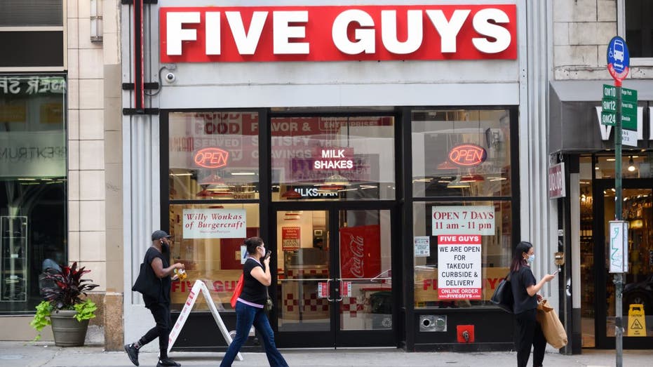 People walking outside a Five Guys restaurant