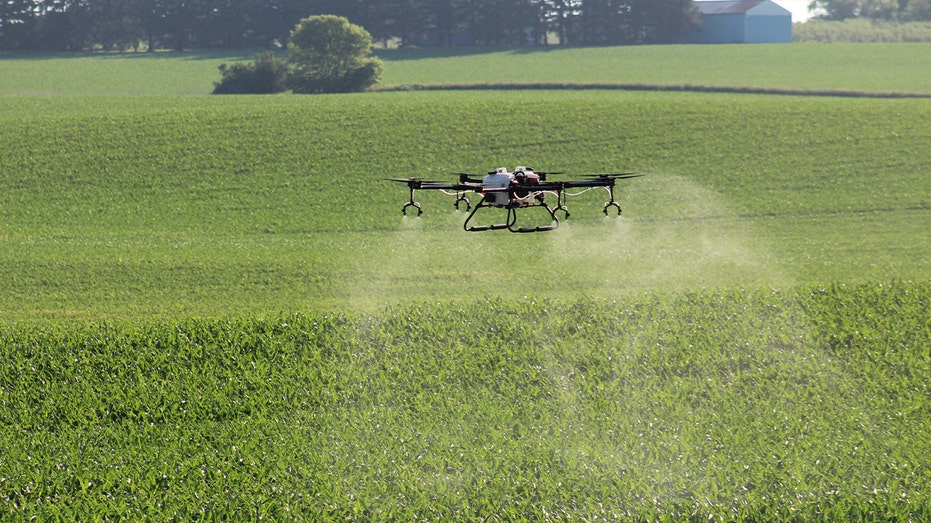 A Hylio sprays chemicals over a green farm field