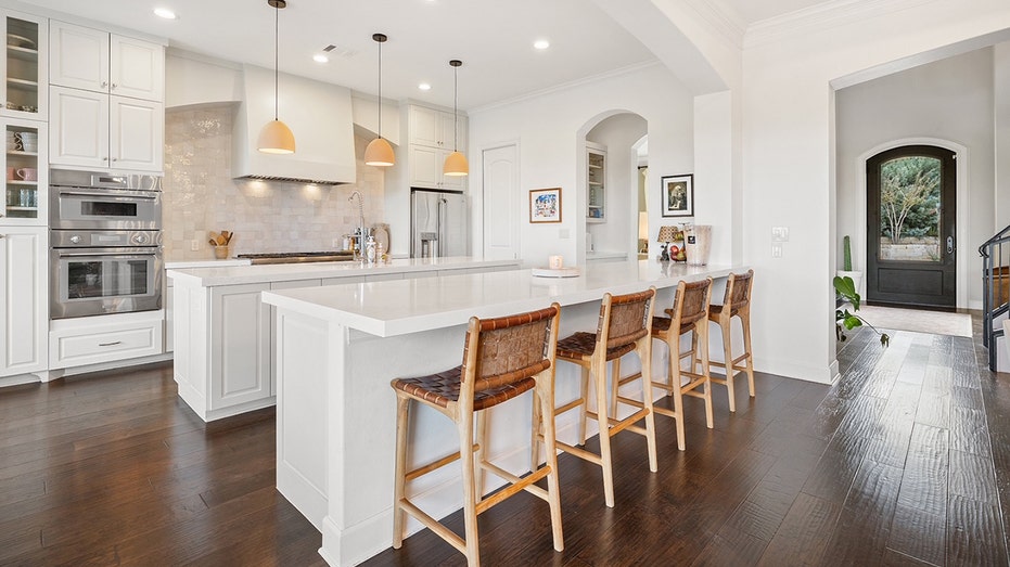 An all white kitchen with wooden chairs