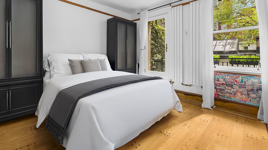 A bedroom with hardwood floors and a bed with white sheets.