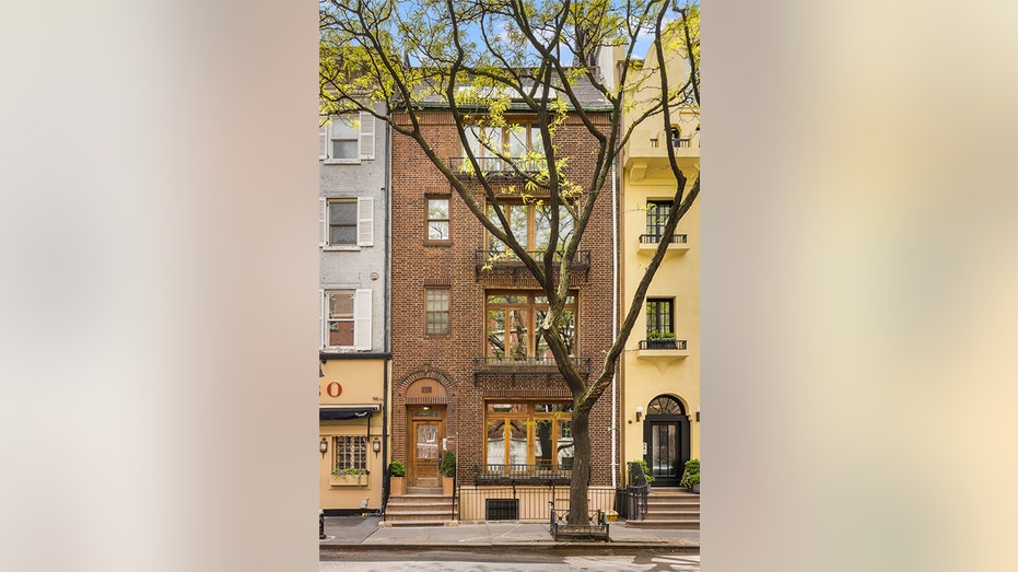 A brick townhouse with a tree in front of it.