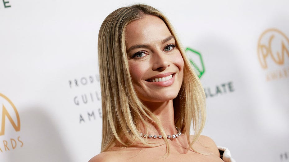 Margot Robbie smiles at the camera with a blunt haircut at her shoulders
