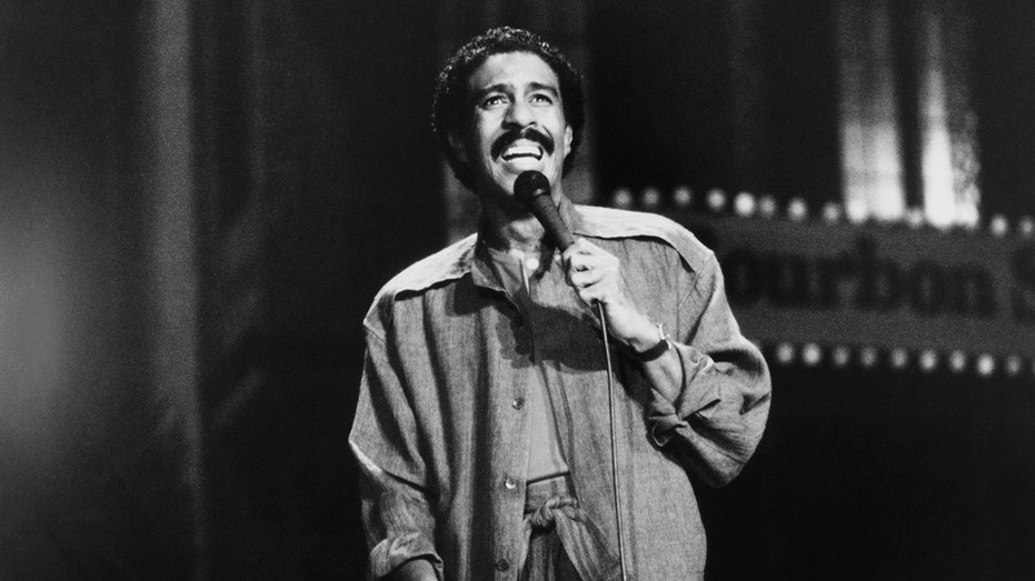 Black and white shot of Richard Pryor smiling while performing on stage