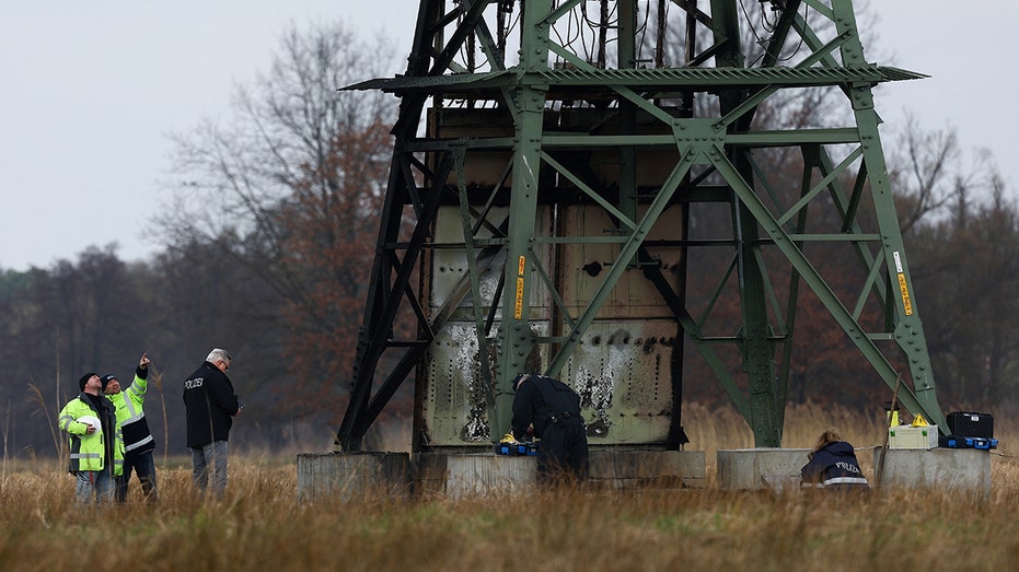 Workers repair an electricity pylon that was set ablaze near Tesla's Gigafactory