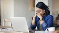 Shot of a young woman looking stressed while using a laptop to work from home