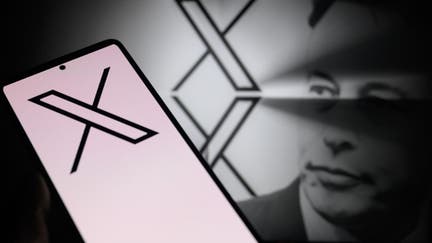 The X logo is being displayed on a smartphone, with the X app, formerly known as Twitter, and X visible in the background, in this photo illustration taken in Brussels, Belgium, on January 5, 2024. 
