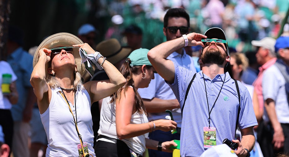 Viewers use special protective glasses to observe a total solar eclipse during a practice round at The Masters Golf Tournament