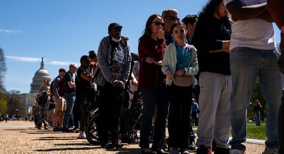 People line up for a few eclipse glasses hand out as they gather on the National Mall