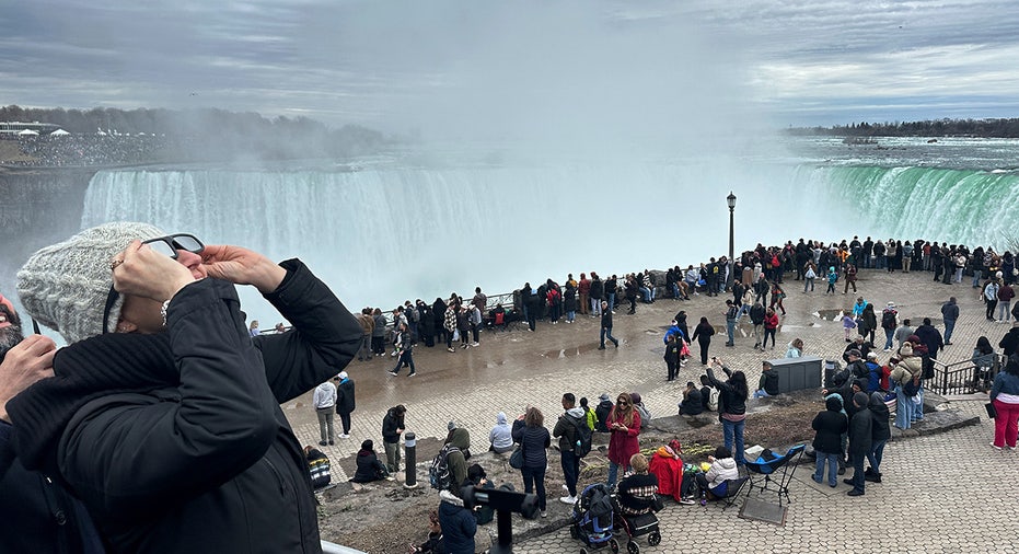 People gather near the Horseshoe Falls to watch the total solar eclipse in Niagara Falls