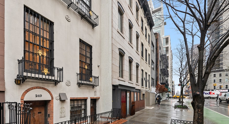 A New York sidewalk featuring the outside of the townhouse.