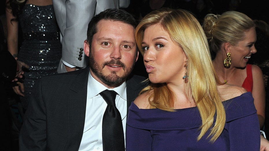 Brandon Blackstock and Kelly Clarkson sit in an audience at an event