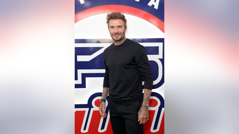 David Beckham poses in front of an F45 sign