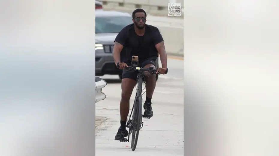 Sean "Diddy" Combs rides a bicycle from his home across the Star Island Bridge in Miami Beach, Florida