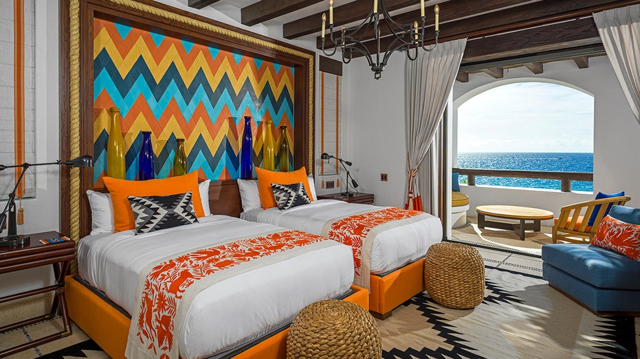 A bedroom with two beds behind a colorful backdrop