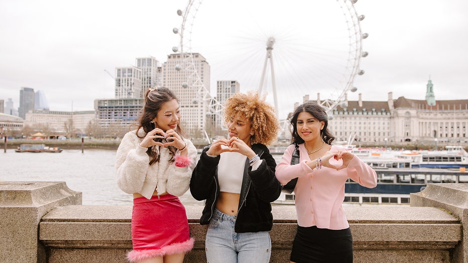 swifties make hand hearts in front of the london eye