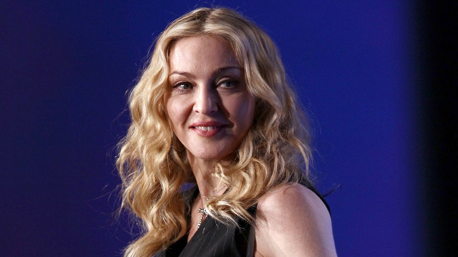 Madonna stands in front of a blue background