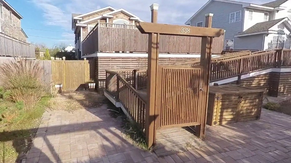 One of Ostrove's Beach Houses on Fire Island, with a wooden gate and ramp leading up to the elevated cottage