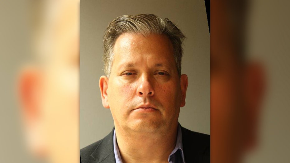 Ostrove frowns in mugshot with disheveled hair