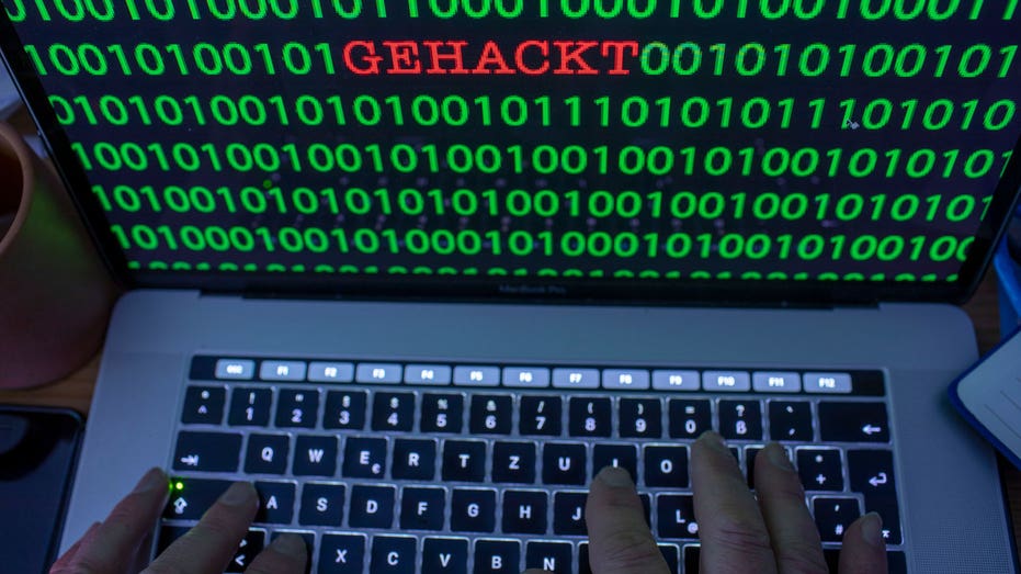 Between the binary code on a laptop monitor you can see the text "GETHACKT"