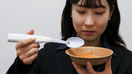 An employee of Kirin Holdings demonstrates an electric spoon, jointly developed with Meiji University&apos;s School of Science and Technology professor Homei Miyashita, that can enhance the salty taste in food, in Tokyo, May 20, 2024.