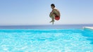 man jumps into an infinity pool