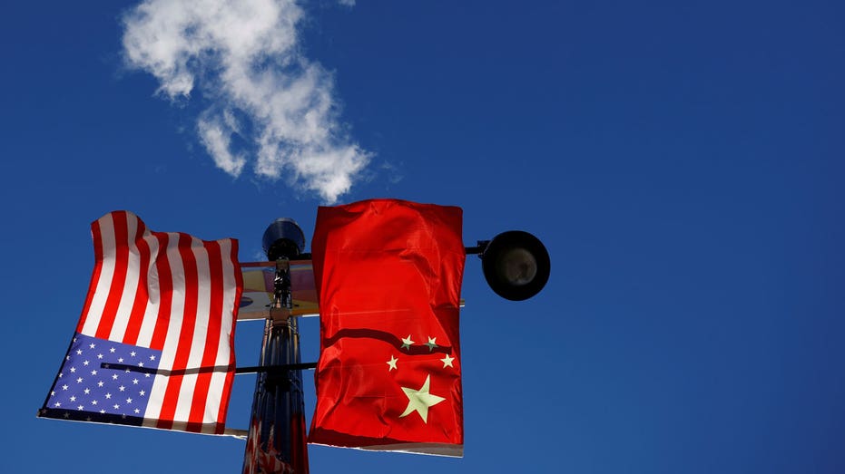 The flags of the United States and China fly from a lamppost in the Chinatown neighborhood of Boston